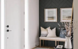 White interior door beside a dark herringbone panelled entry wall with a built-in bench