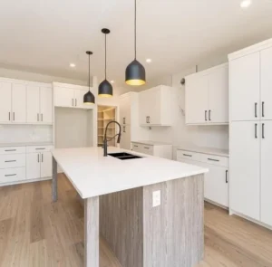 White kitchen with a wood clad island base and black pendant lighting
