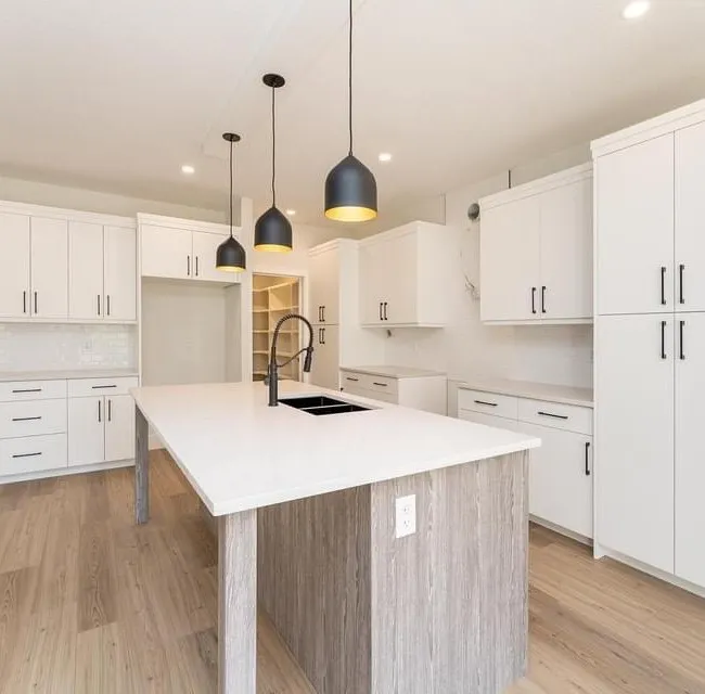 White kitchen with a wood clad island base and black pendant lighting