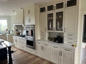 Cream kitchen with glass fronted upper cabinets and a built-in wall oven stack