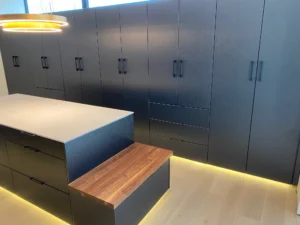 Full height matte dark cabinetry with a timber step and concealed LED lighting