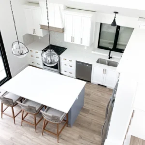 White kitchen with a painted island, pendant lights and bar seating