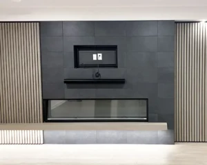 Fireplace feature wall with slatted timber panels either side of dark tile