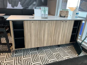 Reception counter in a wood grain finish with open storage behind