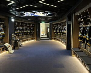 The finished Pro Room at the Spruce Grove Community Centre, a curved run of timber stalls with jerseys hung and lit toe kicks