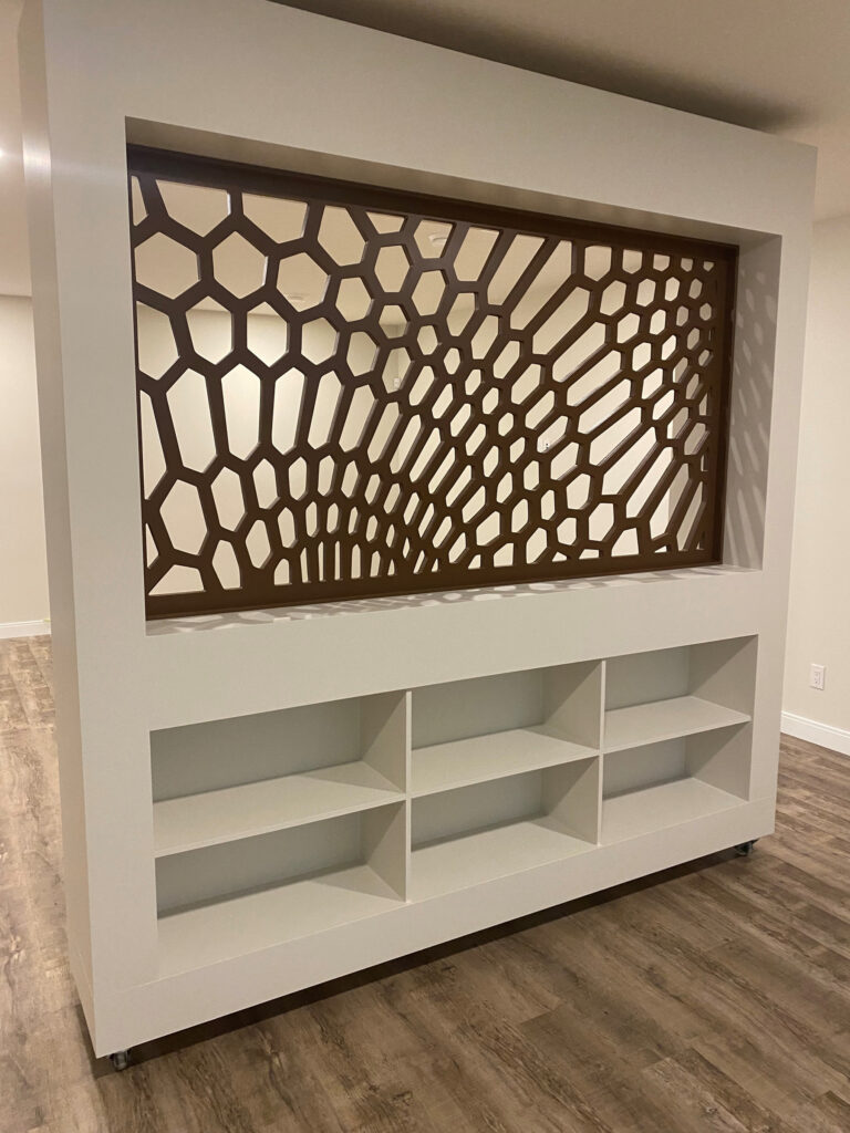 CNC-carved hexagonal screen set into a white room divider with open shelving